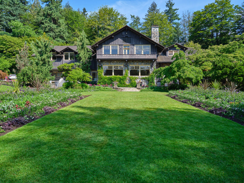 Front view of the Stanley Park Pavilion, a heritage-style building with white trim, dark wooden beams, and a sloping roof, surrounded by trees and gardens in Vancouver’s Stanley Park