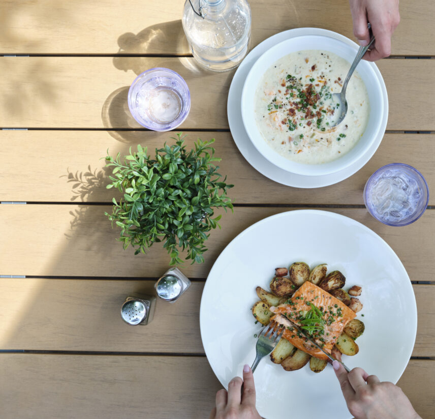 A couple enjoy plates of salmon and chowder on the patio of Stanley's Bar and Grill