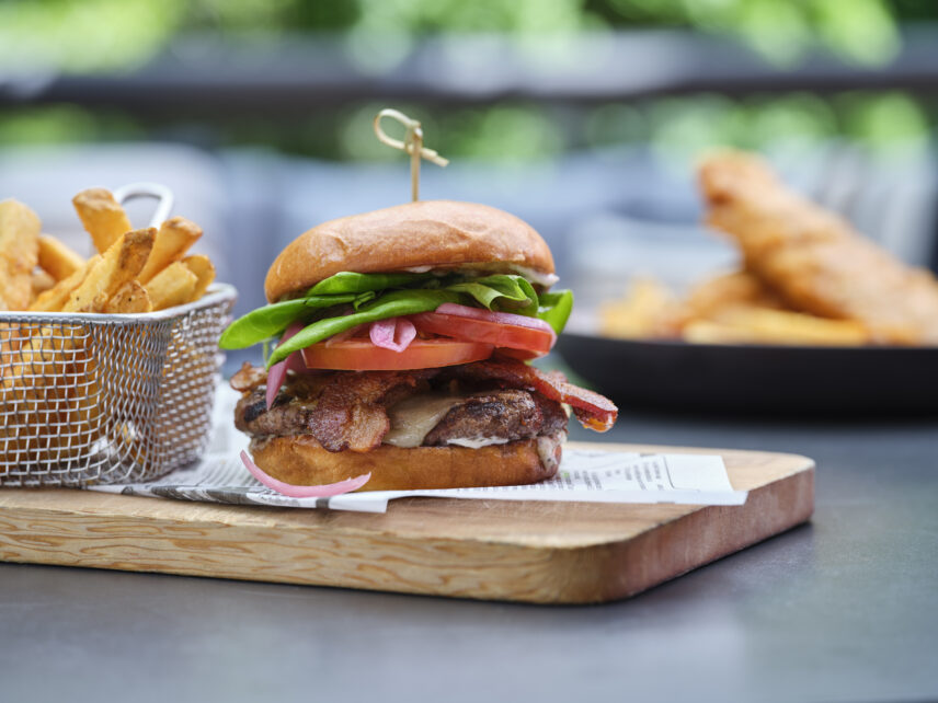 A burger from Stanley's Bar and Grill, with a plate of fish and chips visible in the distance