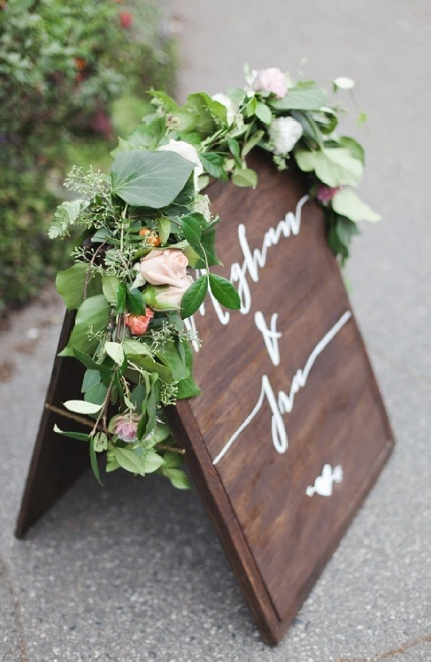 A wedding sign with flowers atop of it
