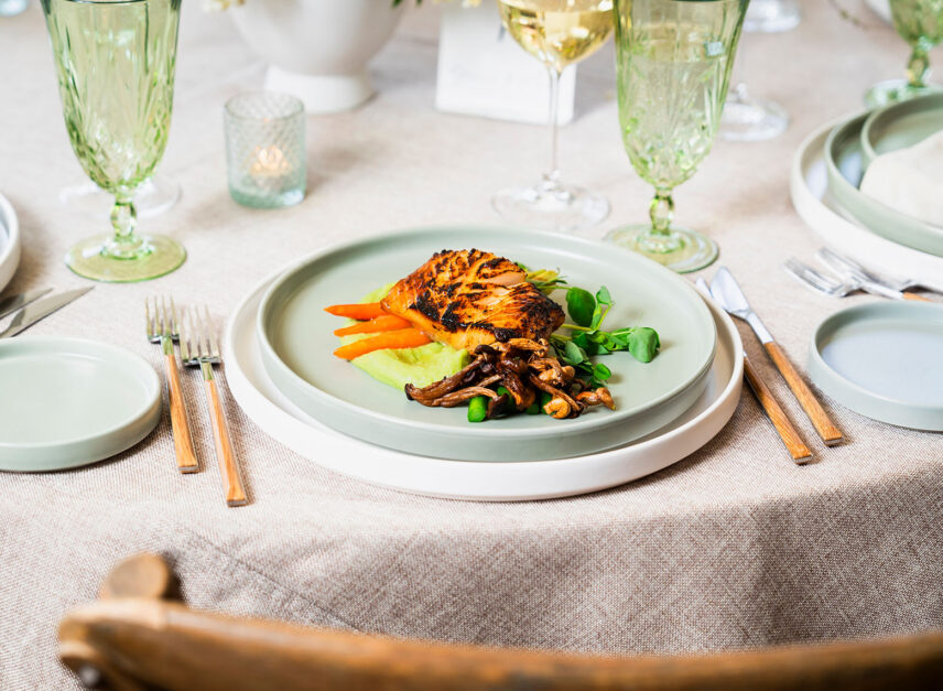 Blackened salmon sits atop a pea mash, with mushrooms and greens
