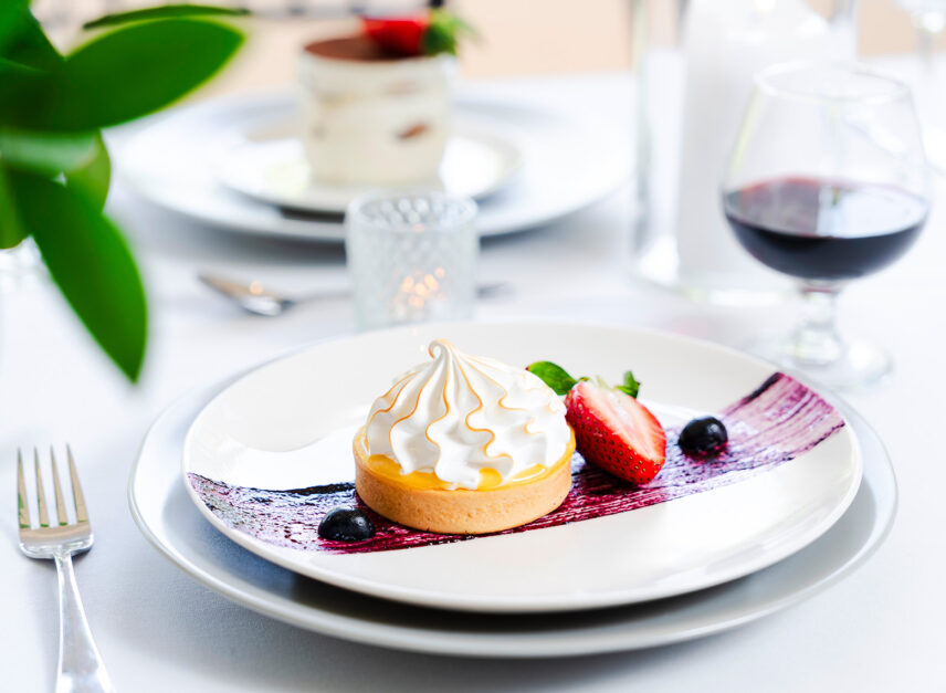 A plate of dessert and fruit sits beside a dessert wine.