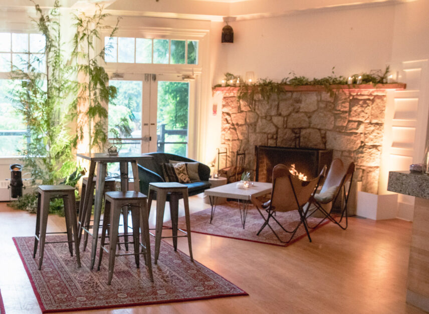 The inside of Stanley's Bar and Grill, cozy chairs and hightop tables rest upon warm rugs, with the fireplace ablaze.