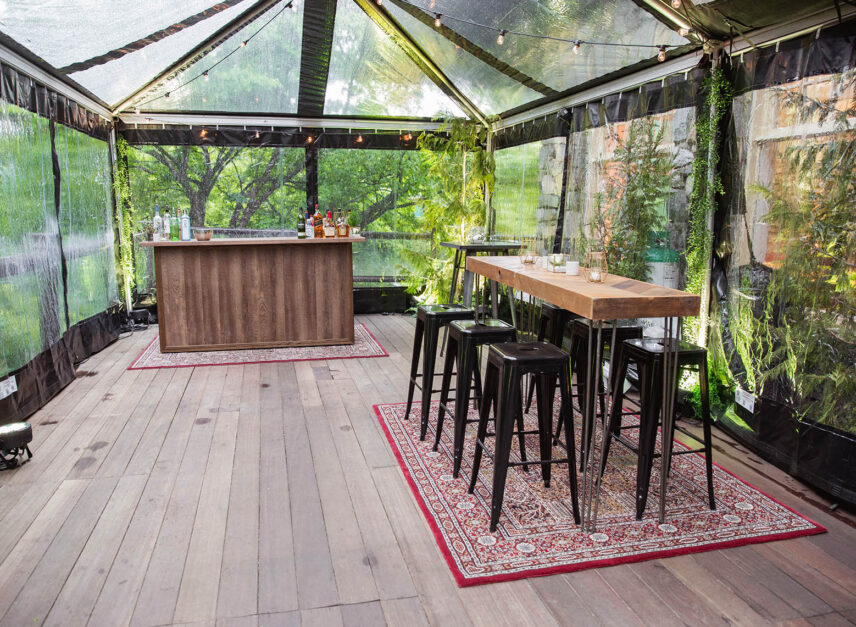 High chairs upon a rug sit within a transparent tent, atop the Stanley's Bar and Grill patio