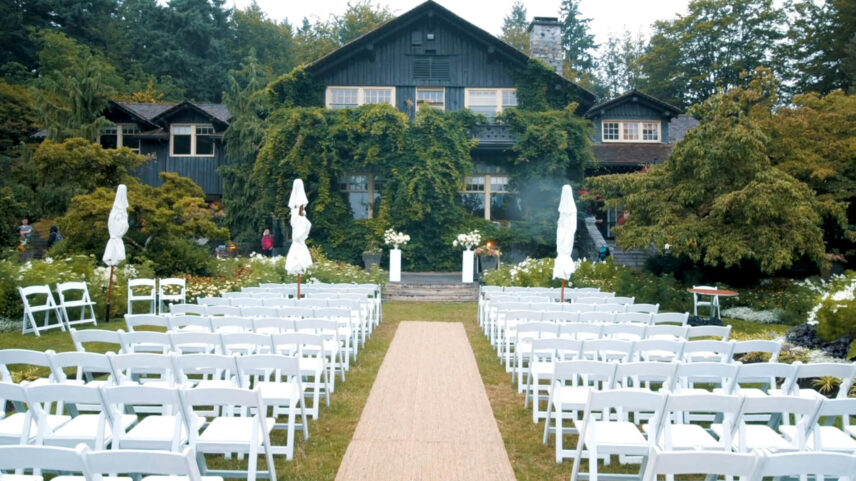 Stanley Park Pavilion, a heritage-style building with white trim and dark wooden beams, partly veiled in mist with trees and gardens faintly visible in the background.